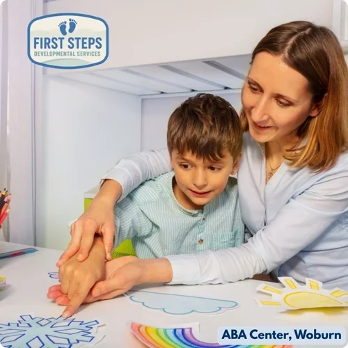 Child engaged in play-based learning with a caregiver at First Steps Developmental Services ABA Center, featuring colorful drawings and a supportive environment.