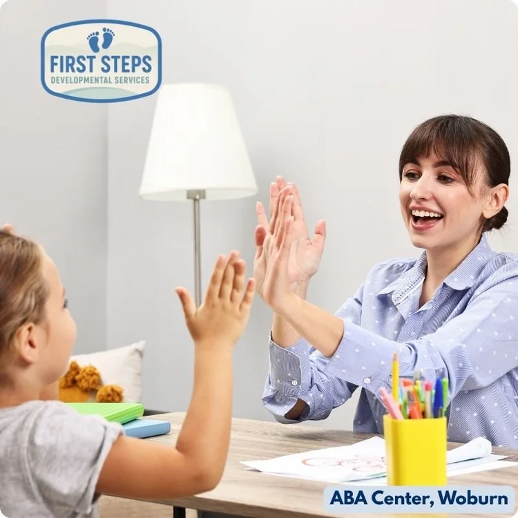 Child and therapist engaging in interactive play at First Steps Developmental Services ABA Center, Woburn, with colorful art supplies on the table, promoting skill development through applied behavior analysis.