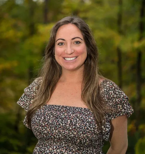 Victoria Yarzebski, MSEd, MS, BCBA, LABA, Early Childhood Development Consultant at First Steps Developmental Services, smiling outdoors with a blurred natural background.